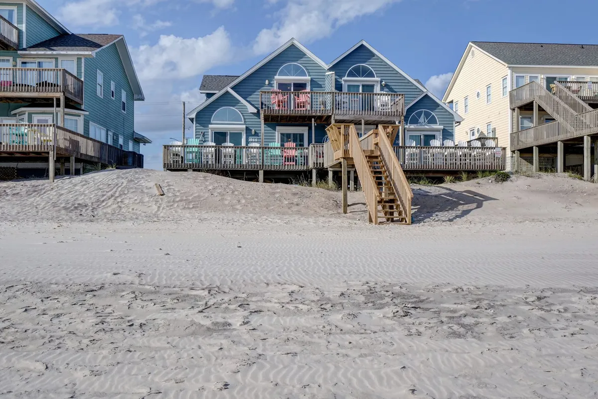 This photo features beachfront houses with wooden stairs leading directly to the sand, colorful balconies, and a lively, open atmosphere perfect for gatherings. The setup encourages easy beach outings and outdoor family activities, echoing the idea of morning shoreline walks and group fun.