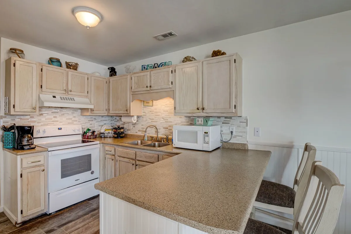 A modern kitchen with sleek countertops, quality appliances, ample cabinetry, and thoughtful decorative touches. The space is designed for both everyday meal preparation and social gatherings, exuding a warm, inviting vibe ideal for group cooking or sharing snacks.