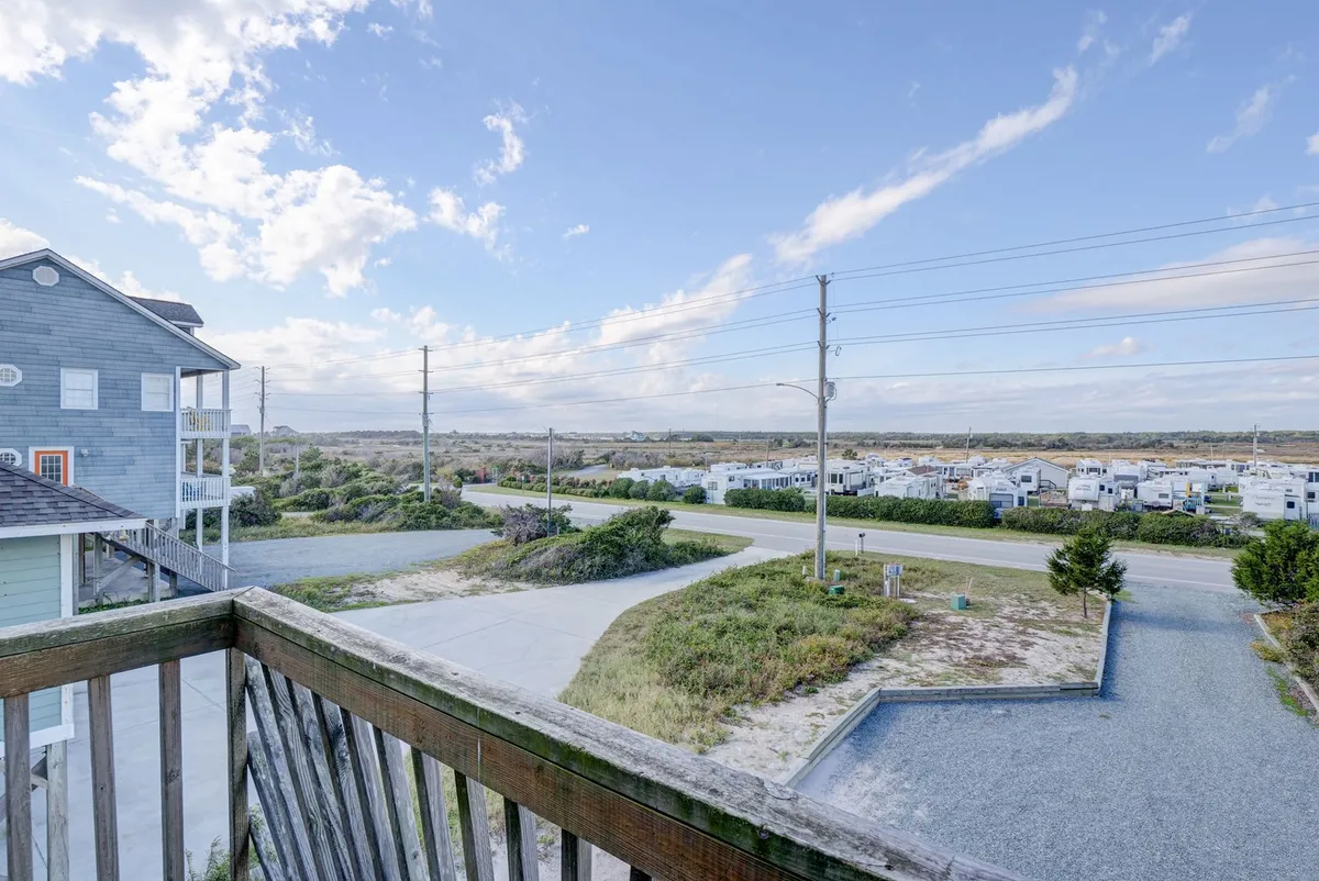 This image presents a peaceful view from the property, capturing a distant landscape with vegetation, power lines, a roadway, and an adjacent building. The scene emphasizes opportunities for enjoying sunrises, stargazing, and unwinding while taking in the natural surroundings.